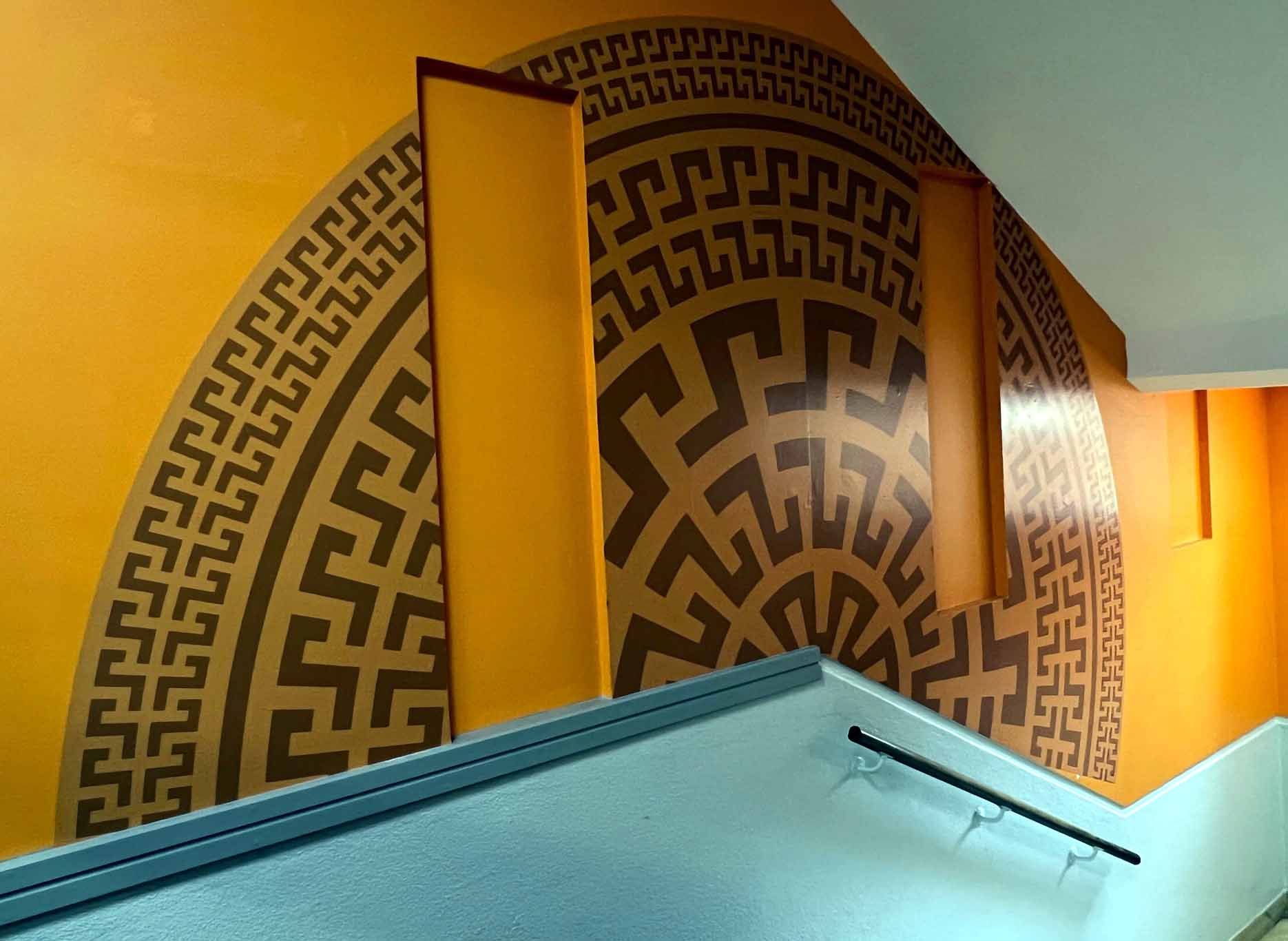 A staircase with a greek key pattern on the wall