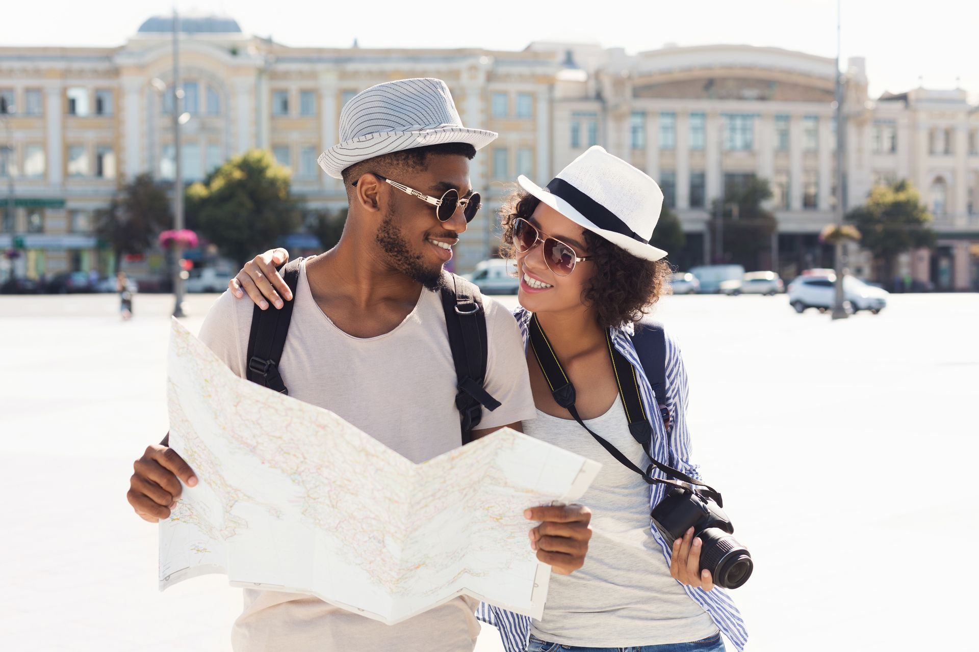 Smiling couple looking at a map, outdoors in a sunny city square