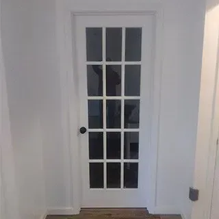 A white french door with glass panels is in a hallway.