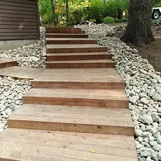 A wooden staircase leading up to a house surrounded by rocks.