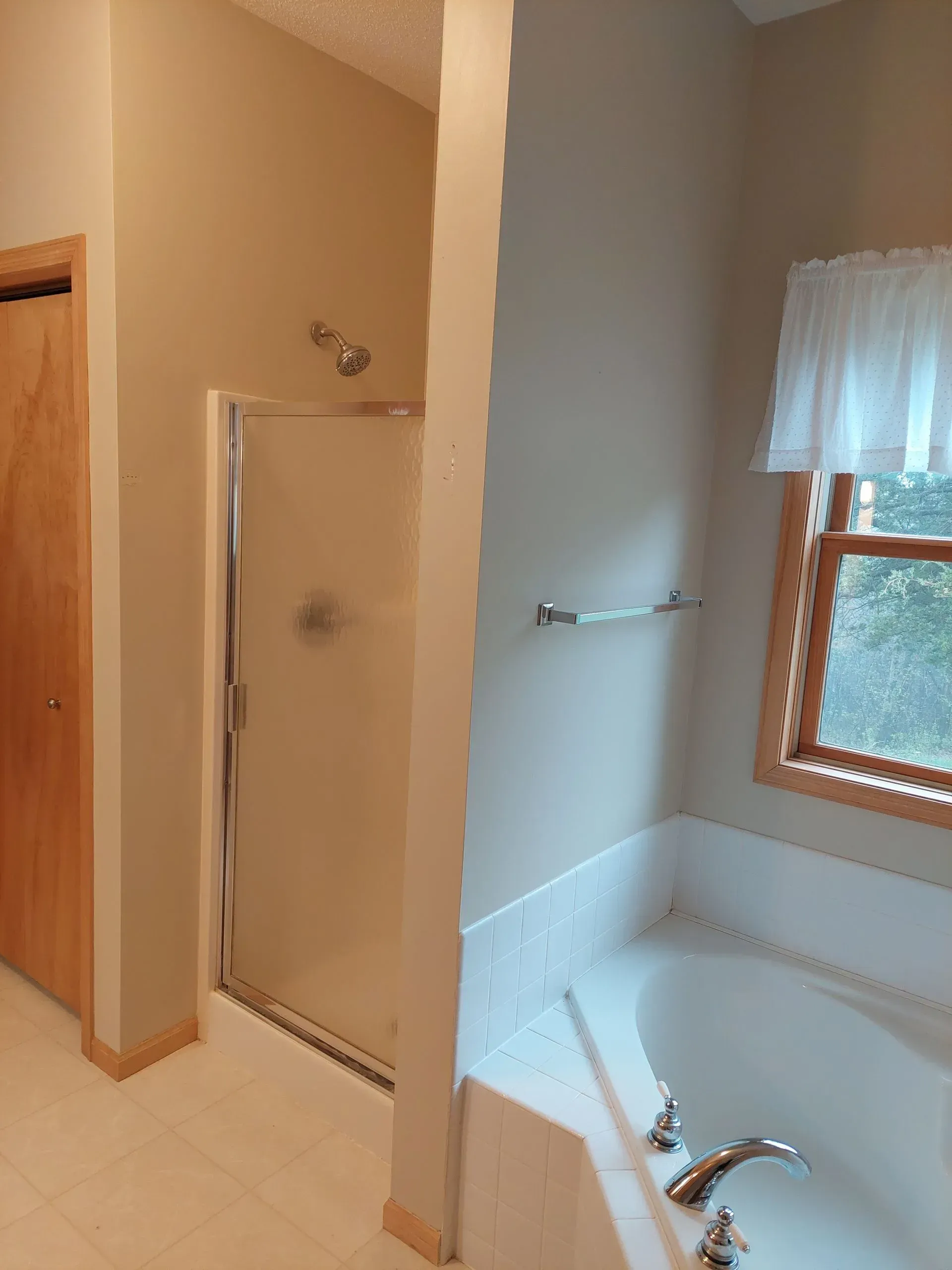 A bathroom with a tub a shower and a window