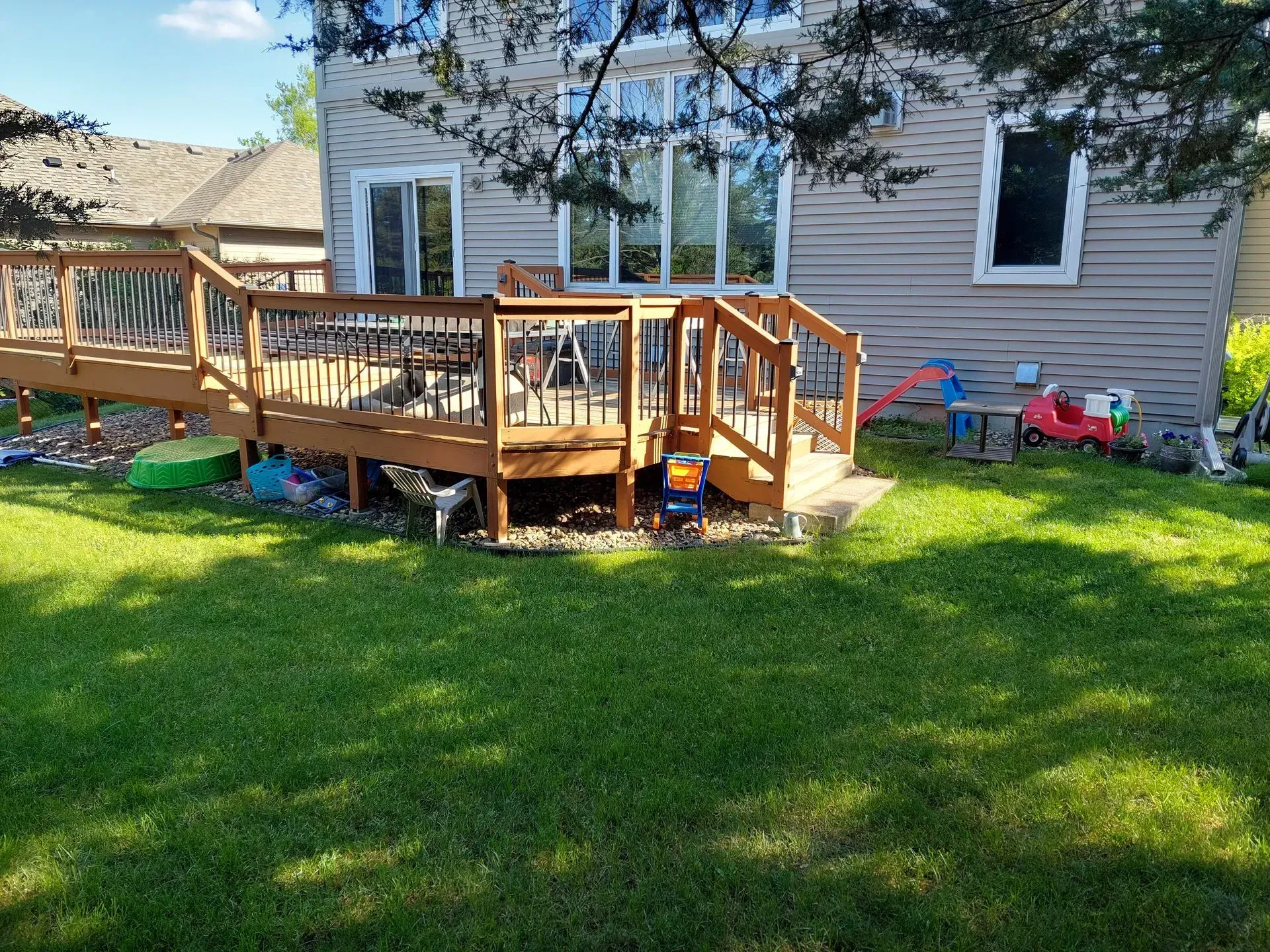 A backyard with a wooden deck and stairs in front of a house.
