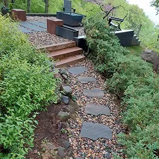 A stone walkway leading to a bench in a garden