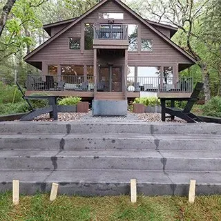 A large house with stairs leading up to it and chairs in front of it.