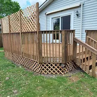 A wooden deck with stairs and a lattice fence in front of a house.