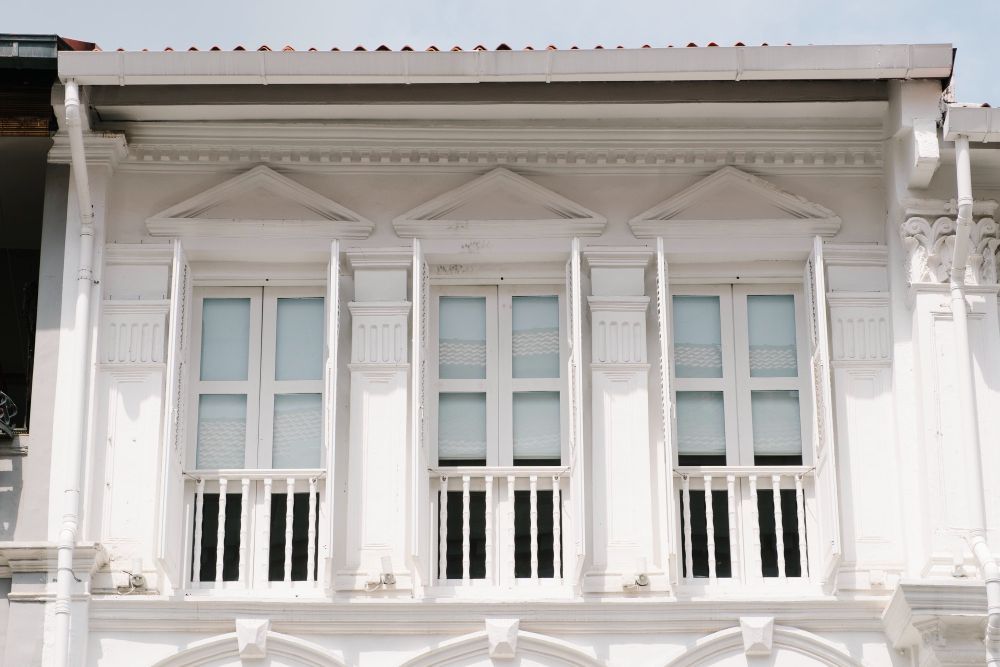White facade with three tall windows, each with two sections and an arched top, set in a classical style.