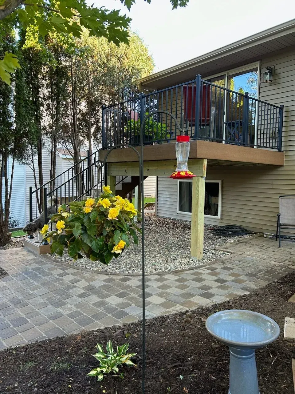 A house with a deck and a bird feeder in front of it