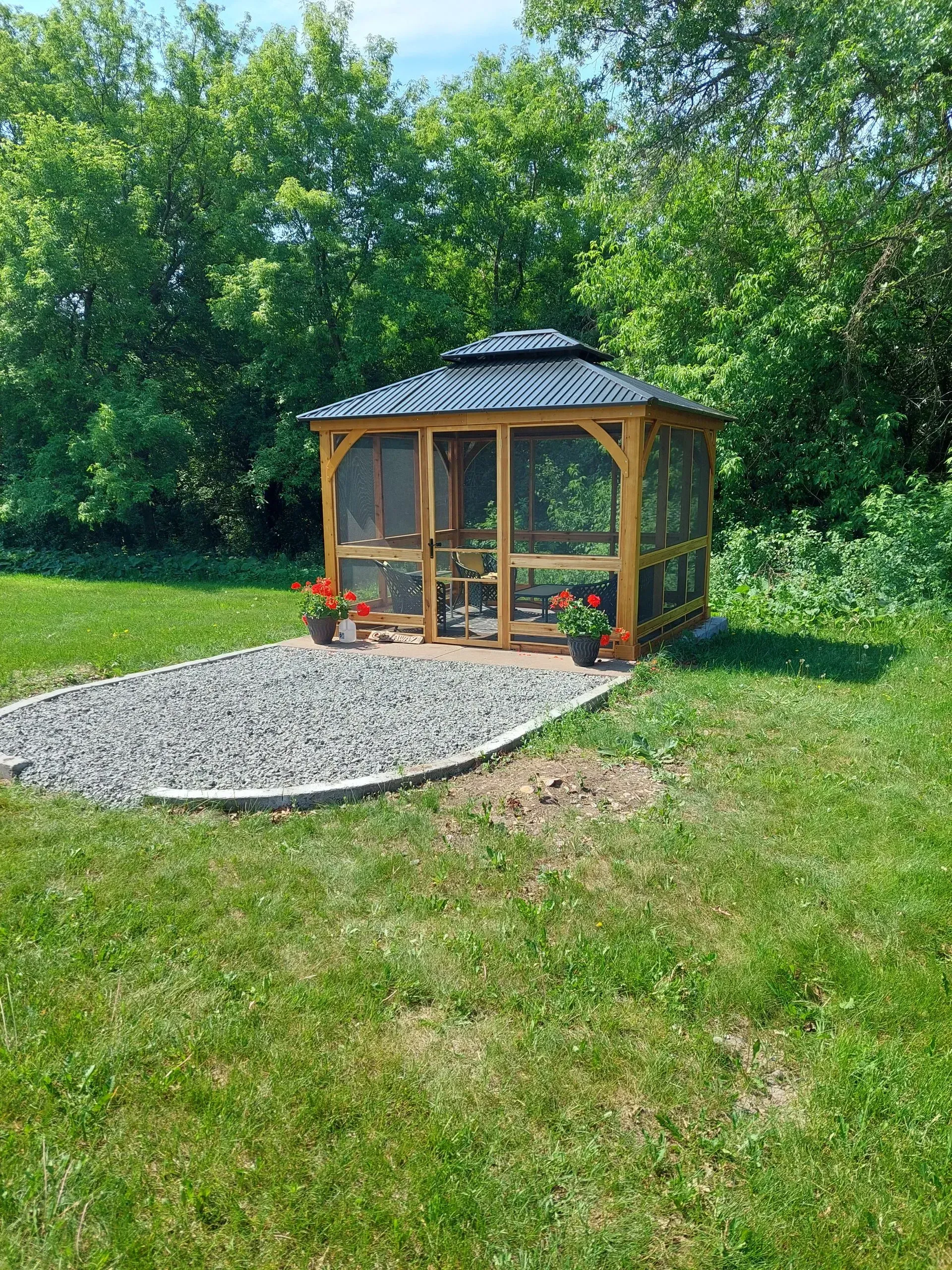 A gazebo is sitting in the middle of a lush green field.