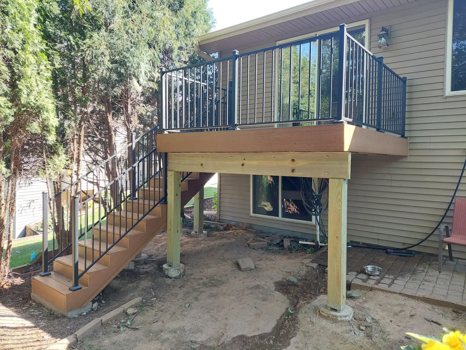 A wooden deck with stairs leading up to it is in front of a house.
