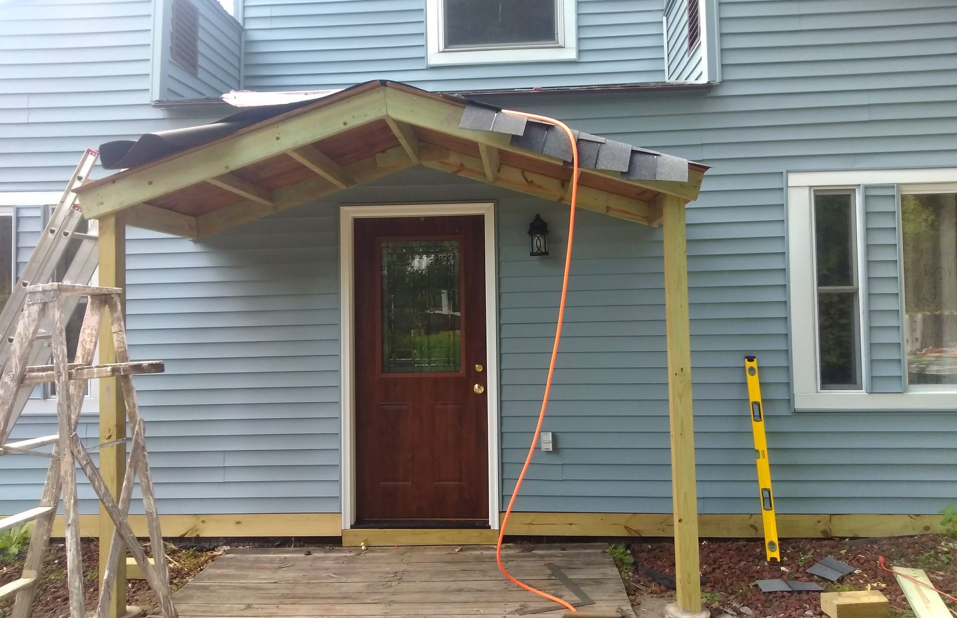 A wooden porch is being built on the side of a house.