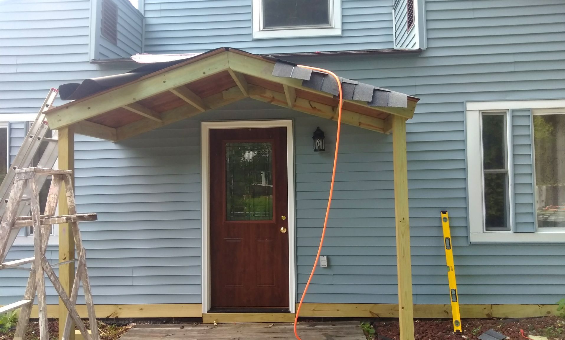 A wooden porch is being built on the side of a house.