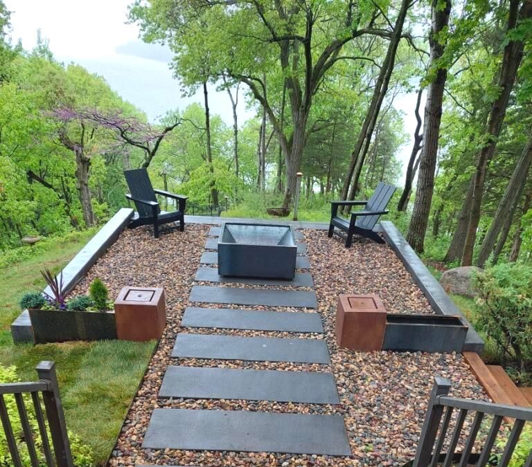 A fire pit sits in the middle of a lush green forest