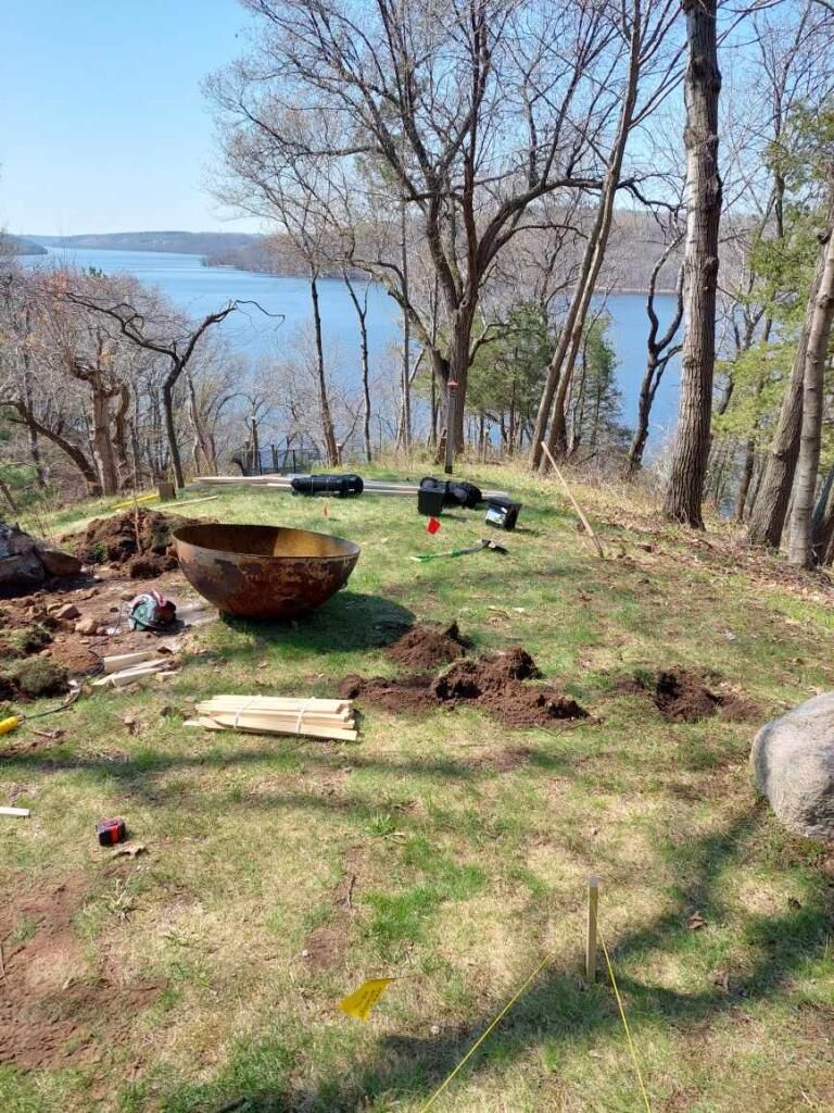 A large bowl is sitting on top of a lush green field next to a lake.