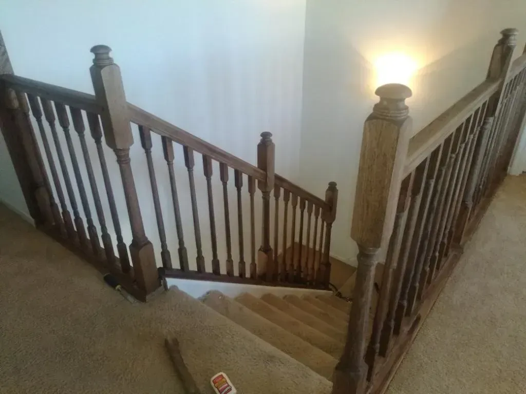 A staircase with a wooden railing and a lamp on the wall.