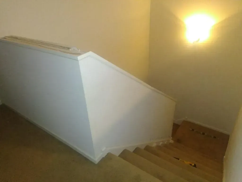 A staircase with a white railing and a light on the wall.
