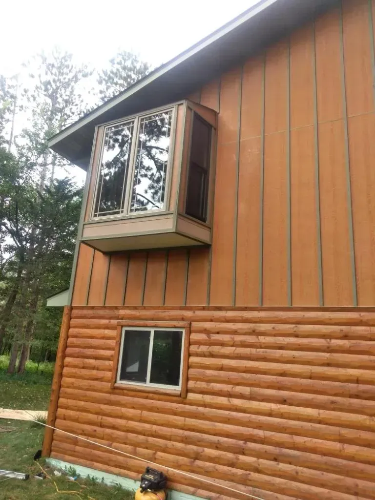 A log cabin with a large bay window on the side of it.