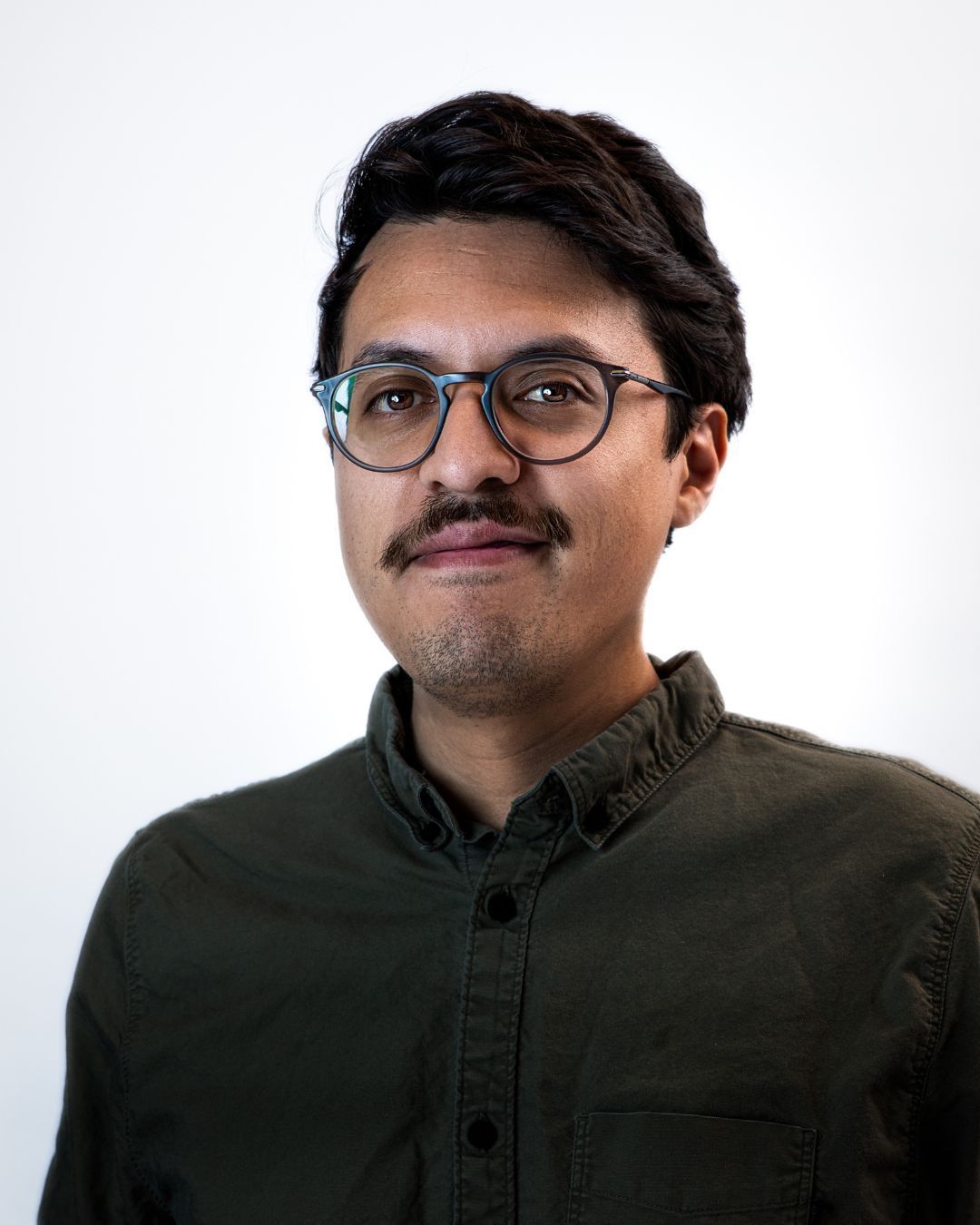 Portrait of a man wearing glasses and a blue plaid shirt against a gray background