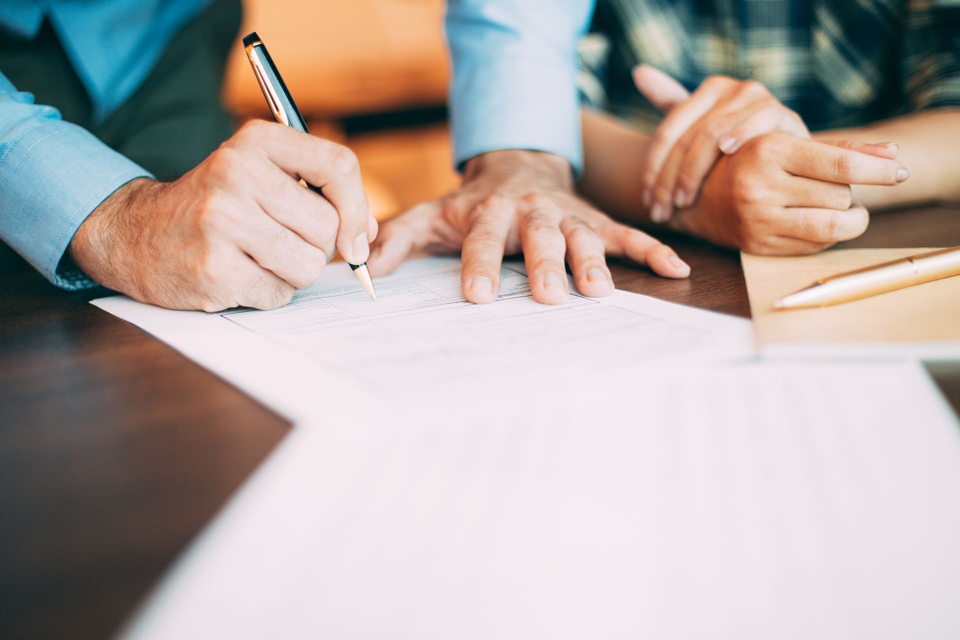 A man and a woman are signing a document at a table.