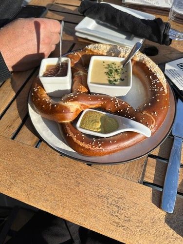 A pretzel with dipping sauces on a plate on a table