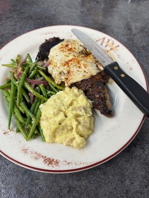 A plate of food with mashed potatoes green beans and a steak