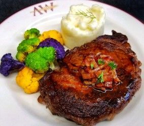 A white plate topped with a steak and vegetables.