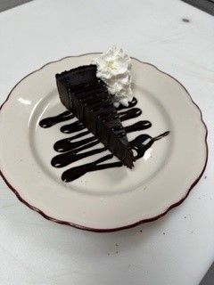 A slice of chocolate cake with whipped cream on a white plate.