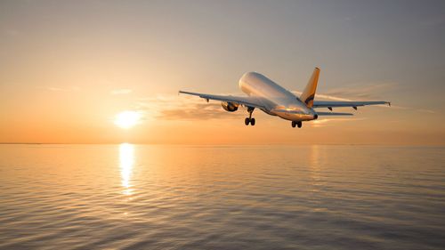 the wing of an airplane is flying through the clouds at sunset .