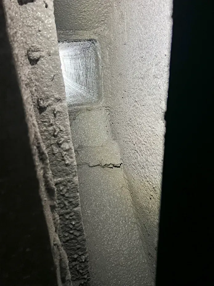 A dusty, metallic structure with a visible crack near the center and a small square opening.