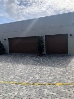 A large house with two garage doors and a brick driveway.