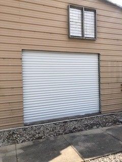 A brown building with a white garage door and two windows.