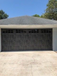A large garage door with a gray roof is sitting in front of a house.