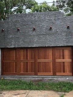 A garage with a wooden door and a gray roof.