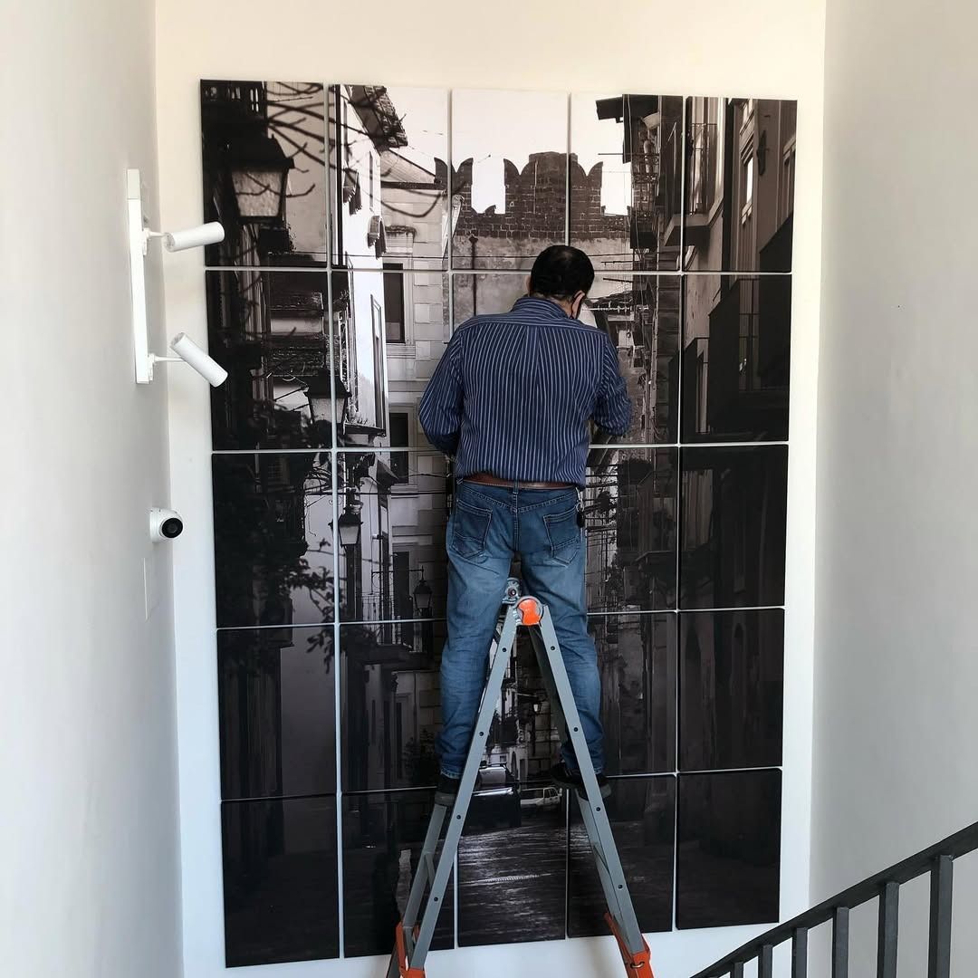 Un uomo su una scala che appende un quadro a un muro