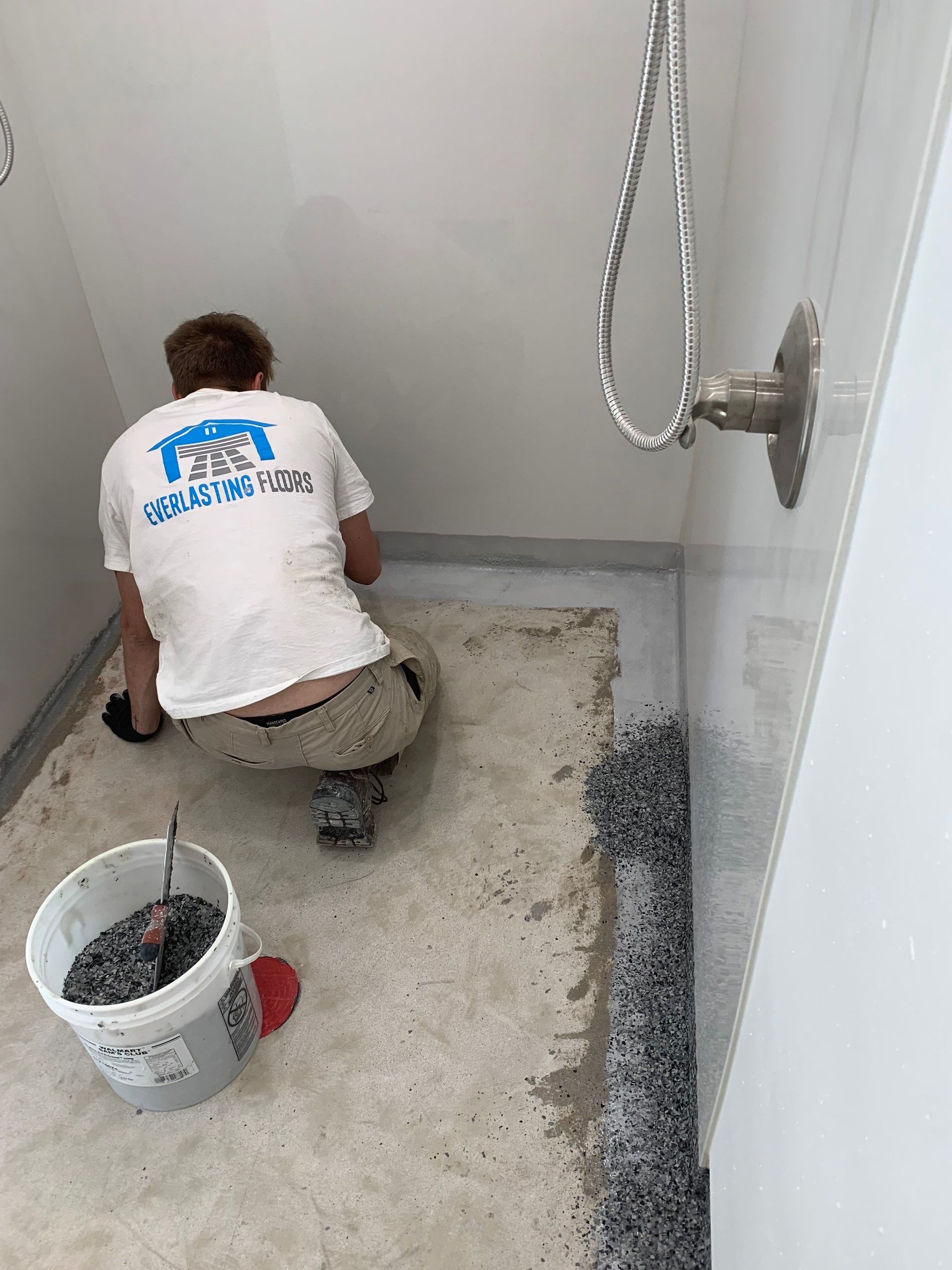 A man is kneeling on the floor in a bathroom.