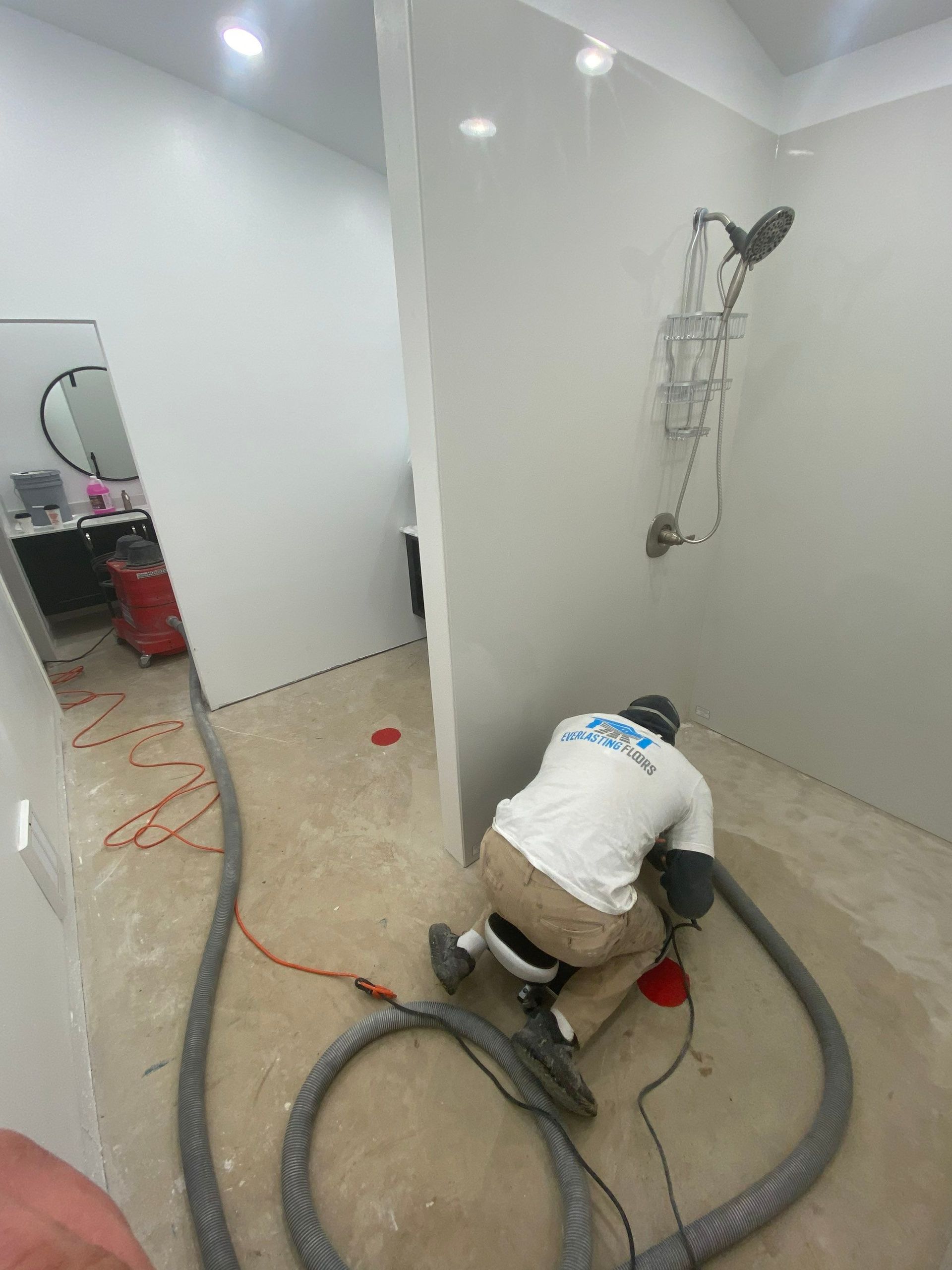 A man is kneeling down in a bathroom with a vacuum cleaner.