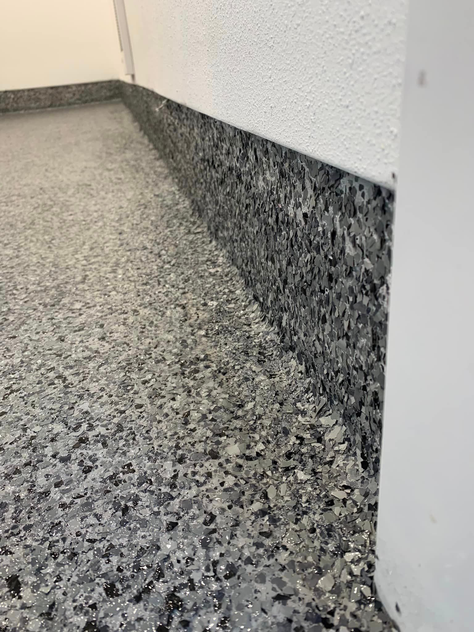 a gray and black floor with a white wall in the background