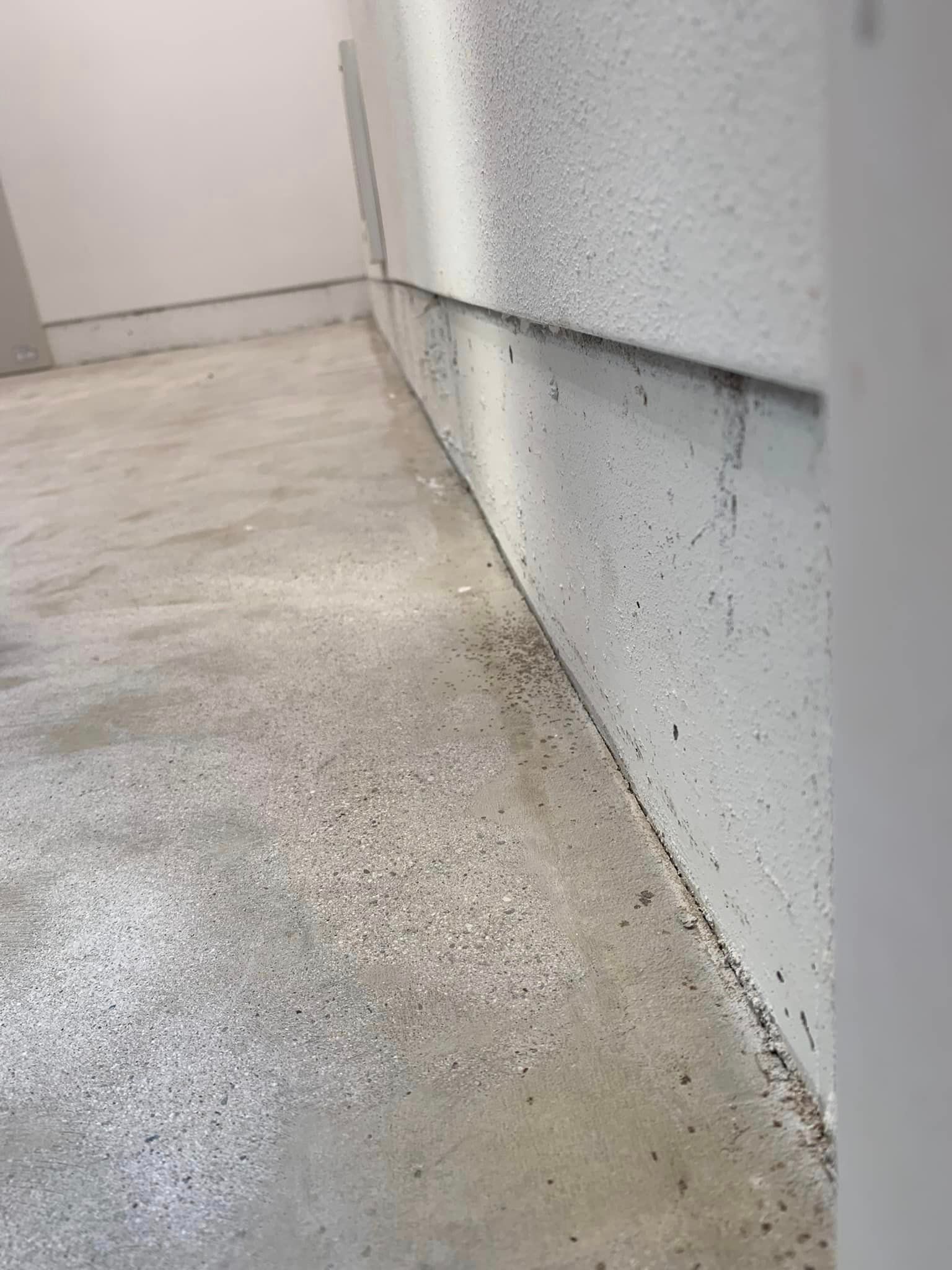 a white wall with a concrete floor in front of it