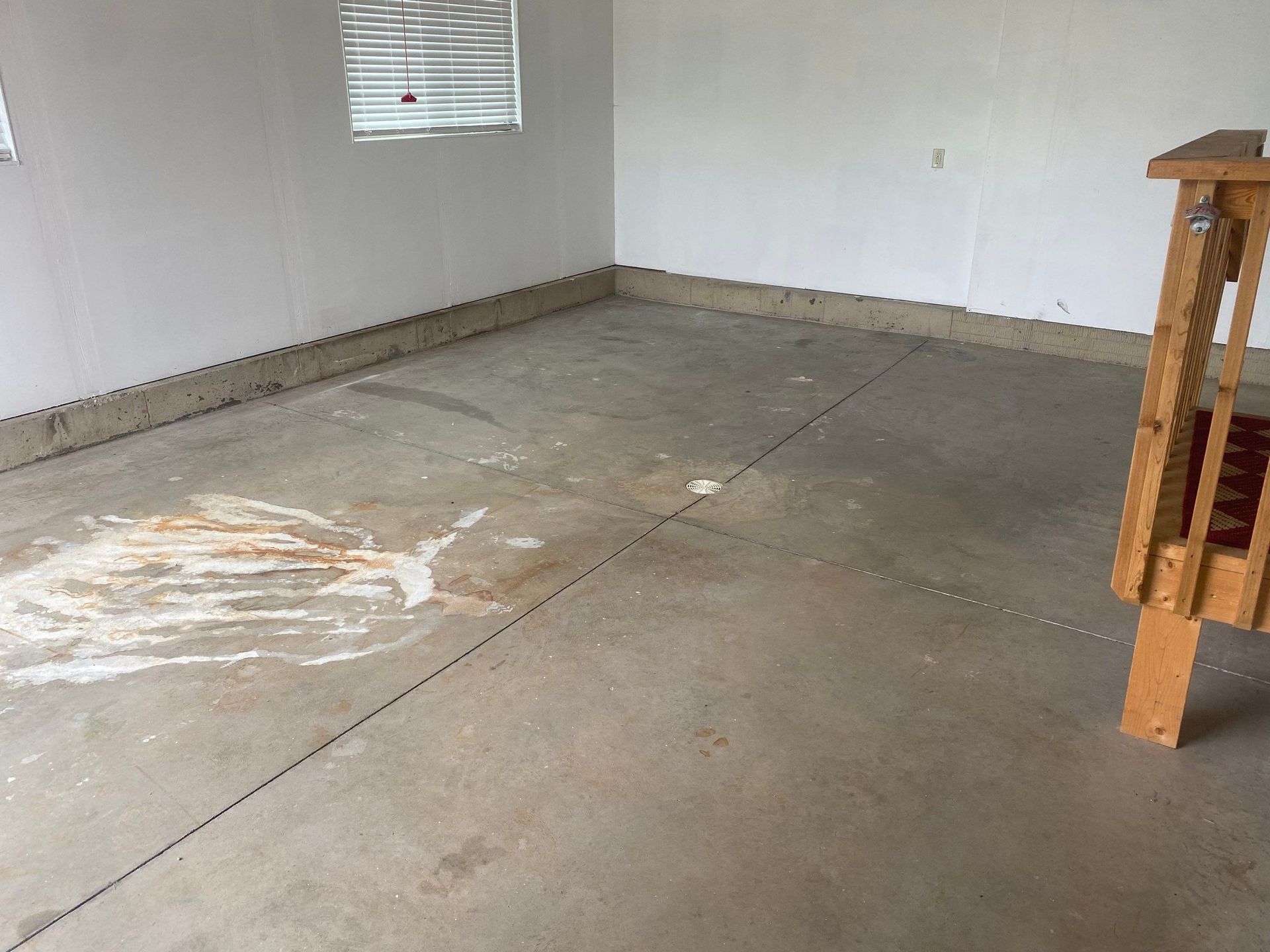 a dirty concrete floor in a garage next to a wooden railing