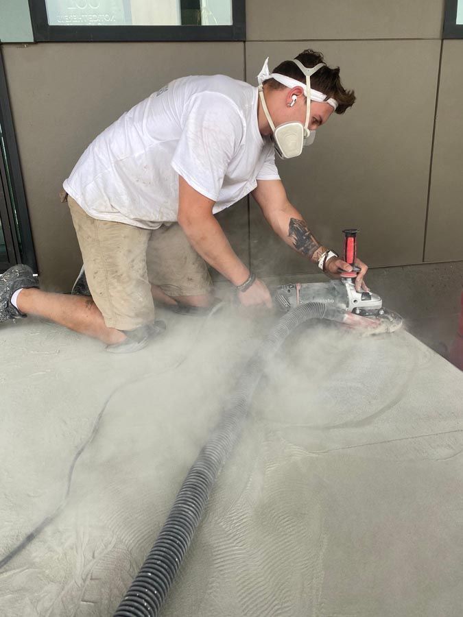 A man wearing a mask is kneeling on the ground using a machine.