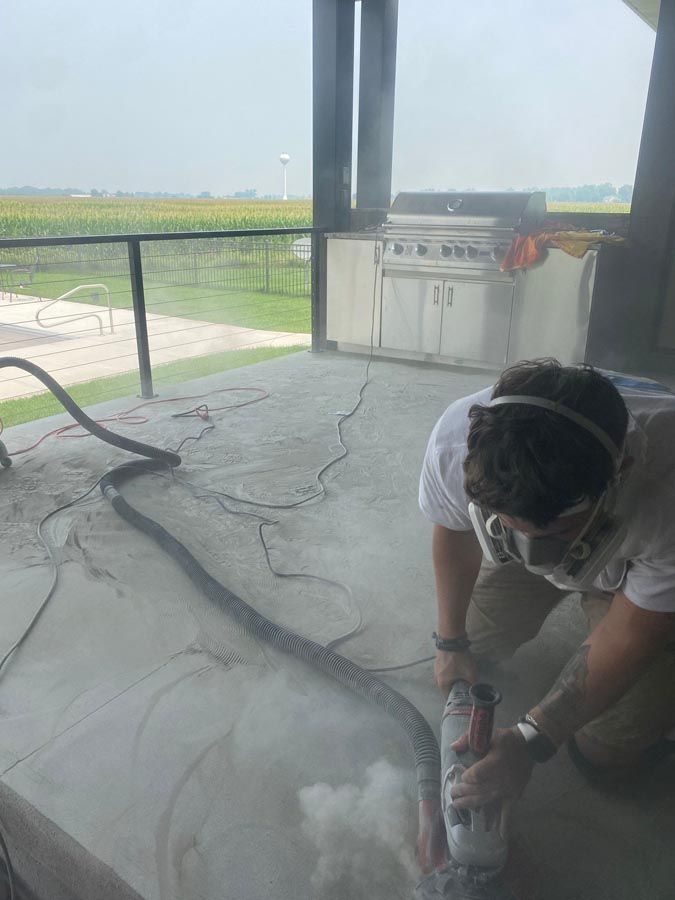 A man is using a grinder on a concrete floor.