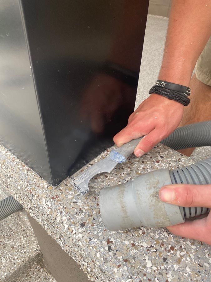 A person is using a vacuum cleaner to clean a counter top.