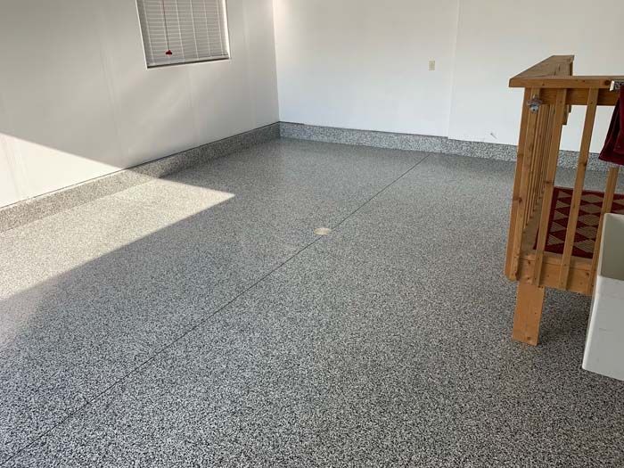 A room with a gray floor and a wooden staircase.