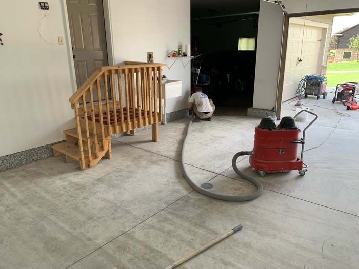 A man is cleaning the floor of a garage with a vacuum cleaner.