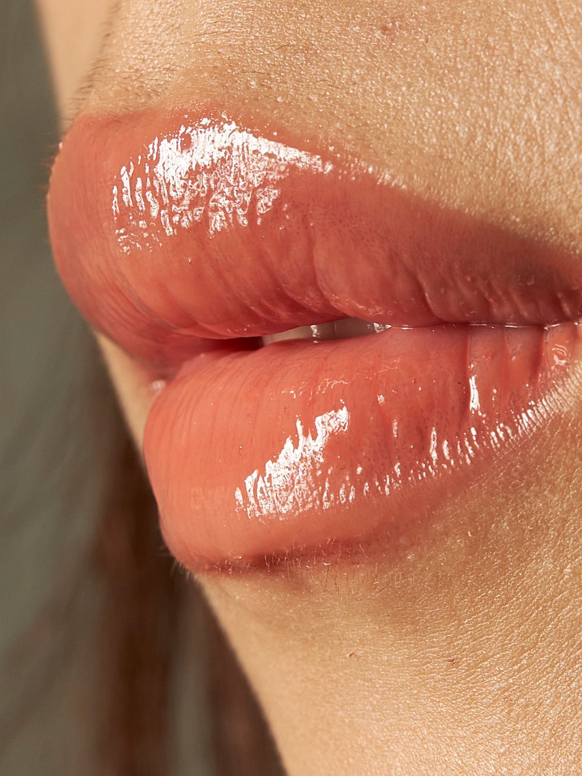 Close-up of a person's lips. The lips are glossy and appear pinkish-brown in color.