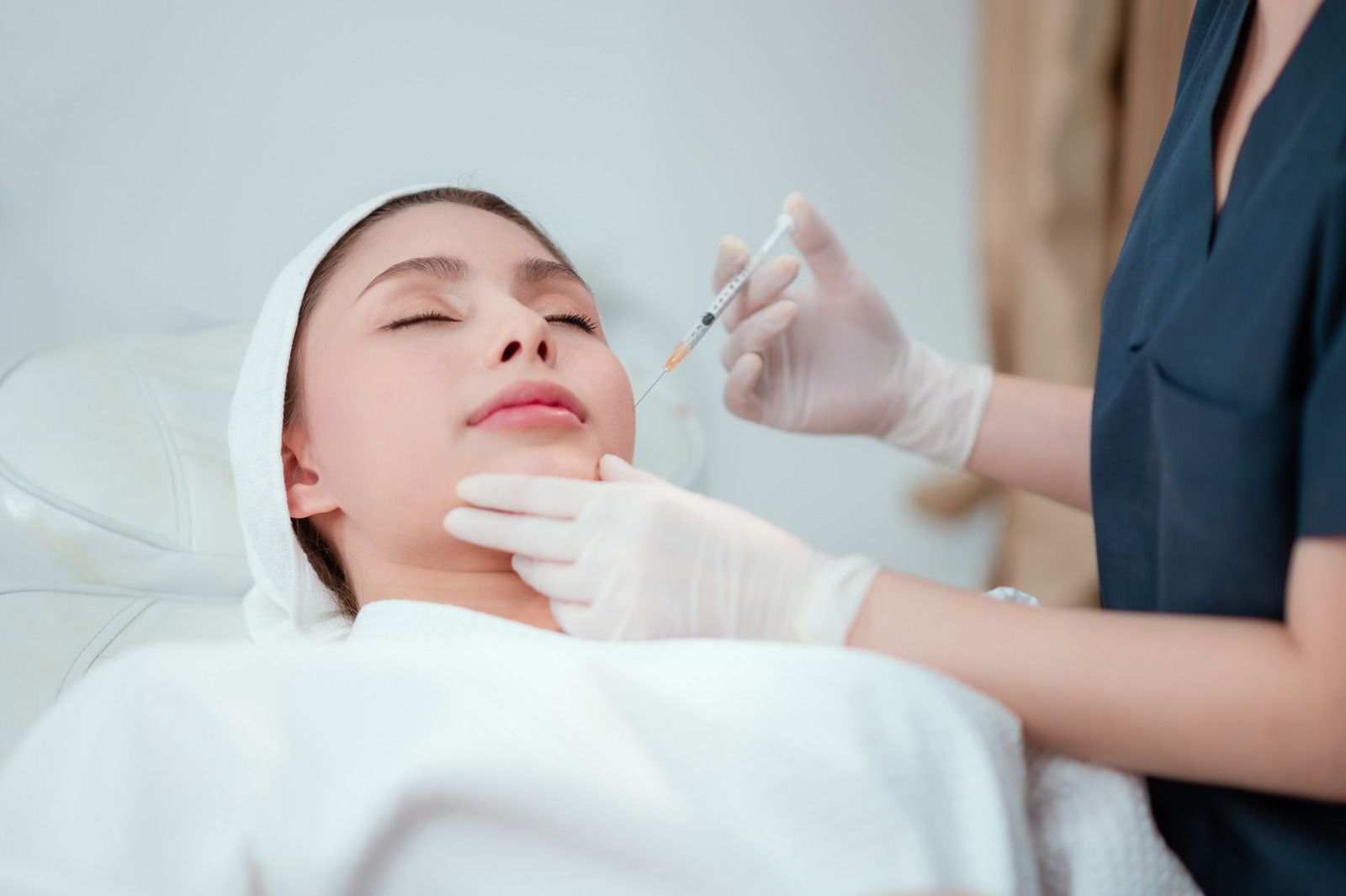 Woman with closed eyes, glowing skin, soft makeup. Brown background with autumn leaves.