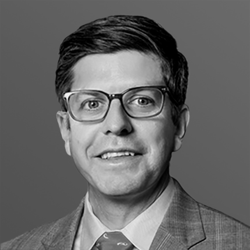 Man wearing glasses and a suit smiling at the camera.