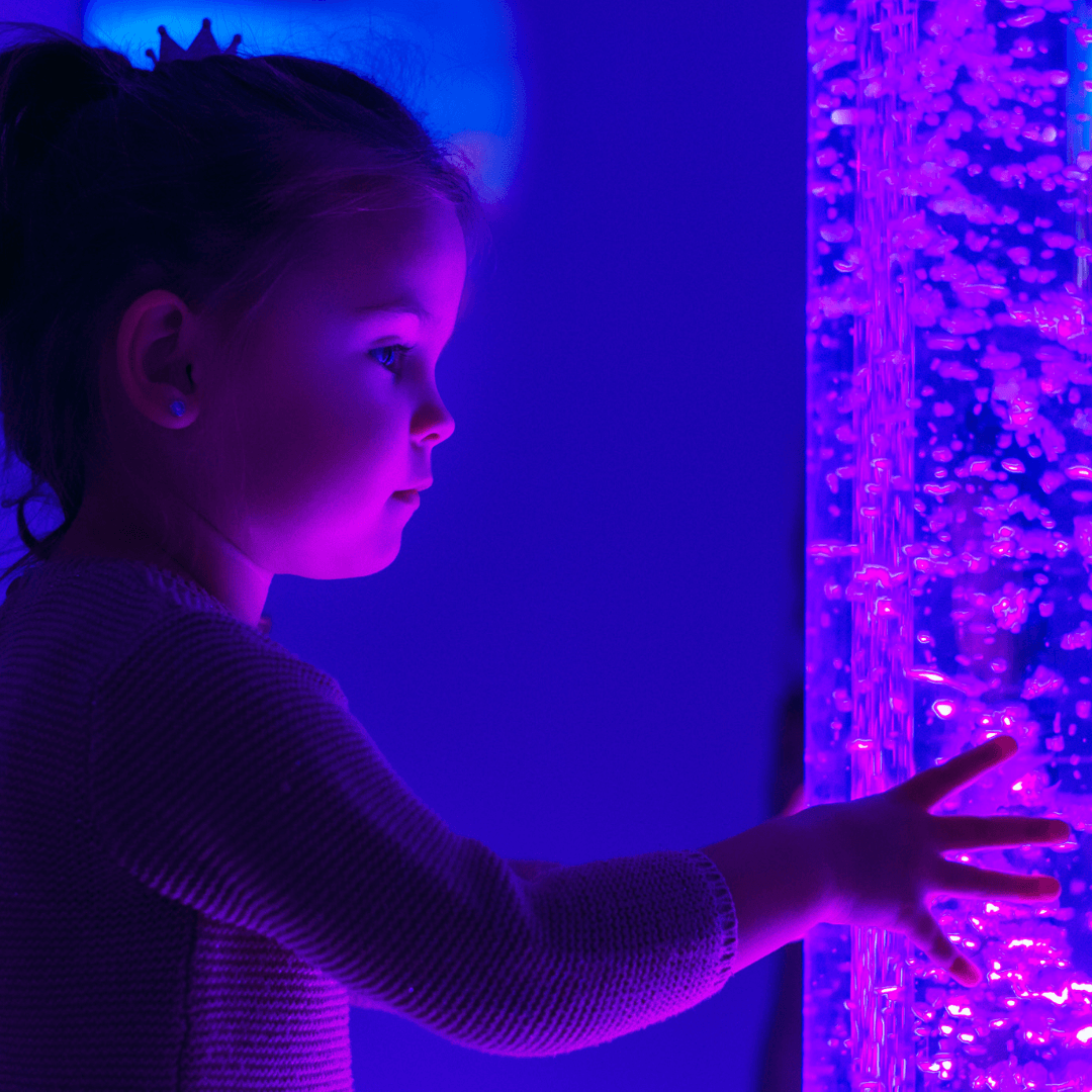A little girl is playing with a purple bubble tube. Autism | Dramatherapy Ireland