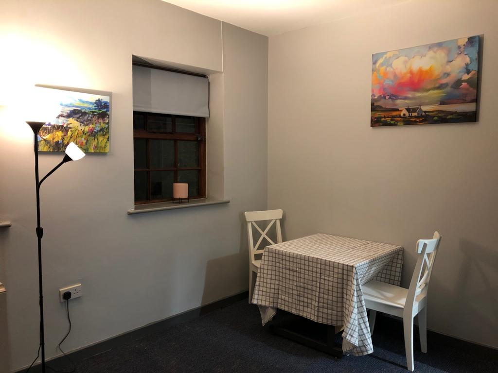 A room with a table and chairs and a painting on the wall. Dramatherapy Ireland