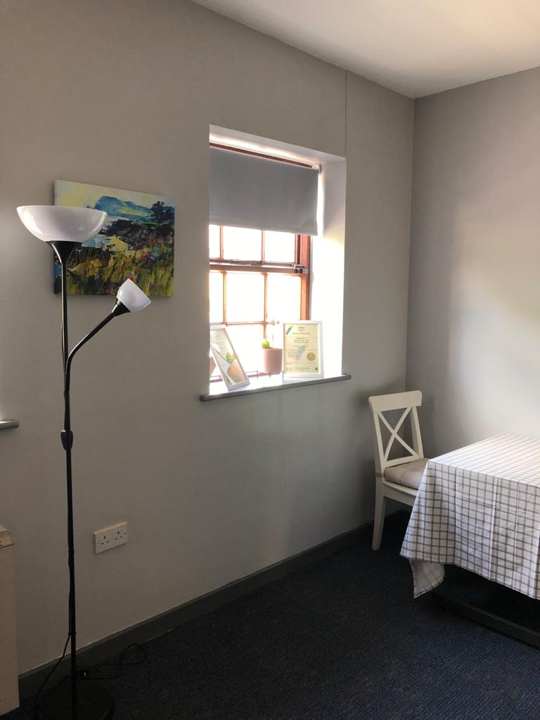 A bedroom with a bed , chair , lamp and window. Dramatherapy Ireland