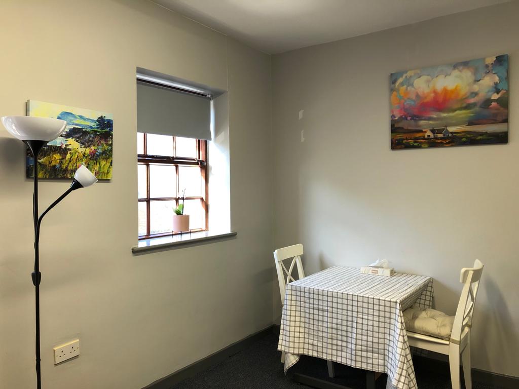 A room with a table and chairs and a painting on the wall. Dramatherapy Ireland